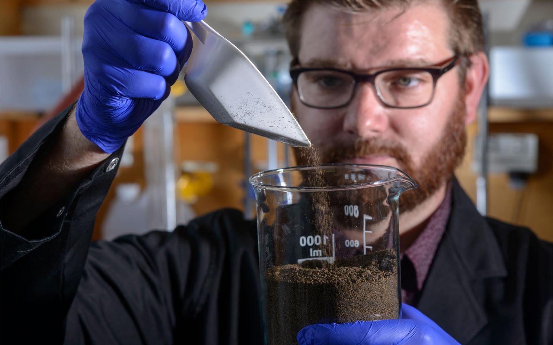 Scientist pouring a soil sample into a beaker