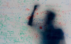 Translucent whiteboard covered in equations and scribbles Translucent whiteboard covered in equations and scribbles