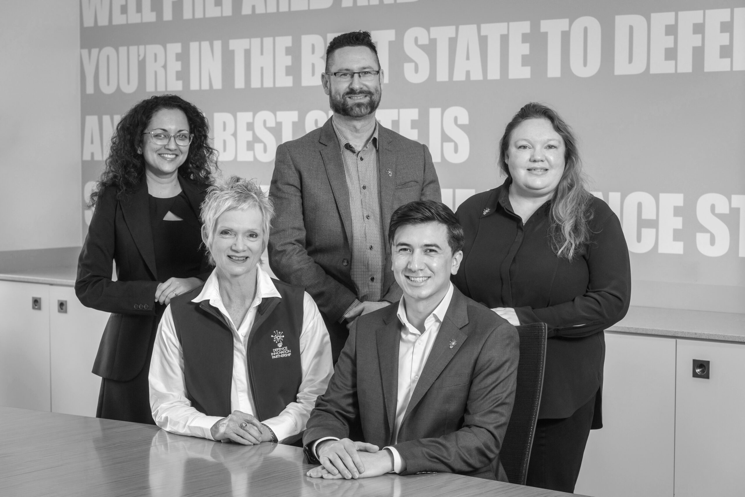 Black and white group photo of the DIP team in a board room